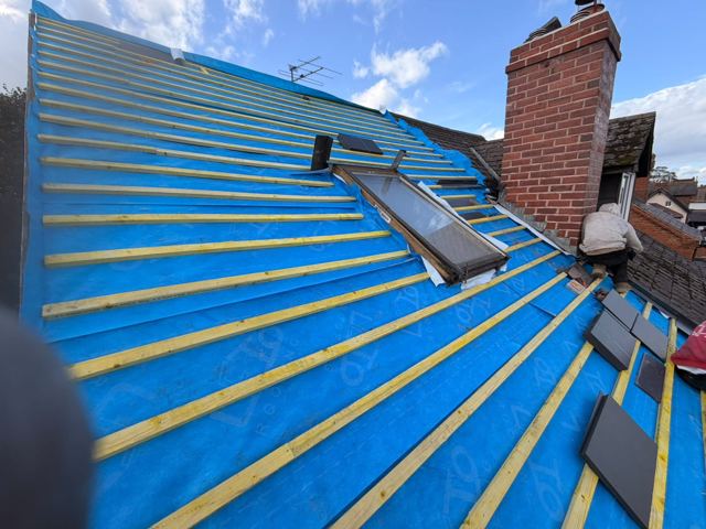 Roof with new membrane and battens and slates ready to be fixed, with a chimney stack