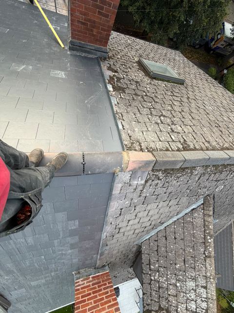 New slate next to older weathered slate beside a chimney and roof window