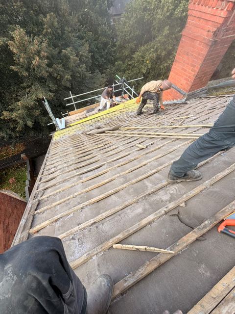 Roofers stripping old felt and battens from a roof on scaffold in Kidderminster